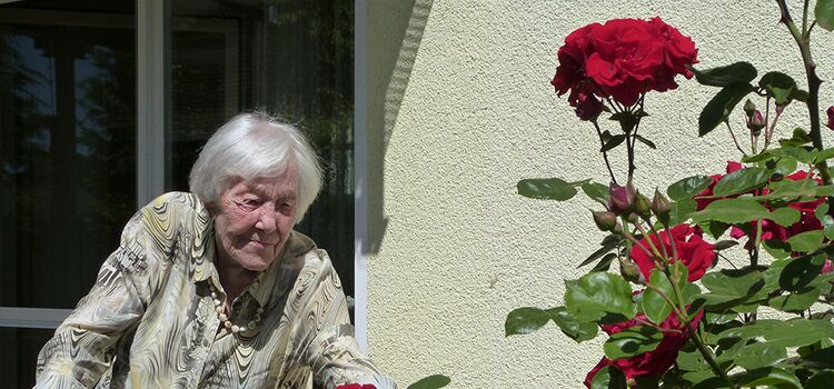 Eine Frau schaut sich die Rosen vor Ihrem Balkon an