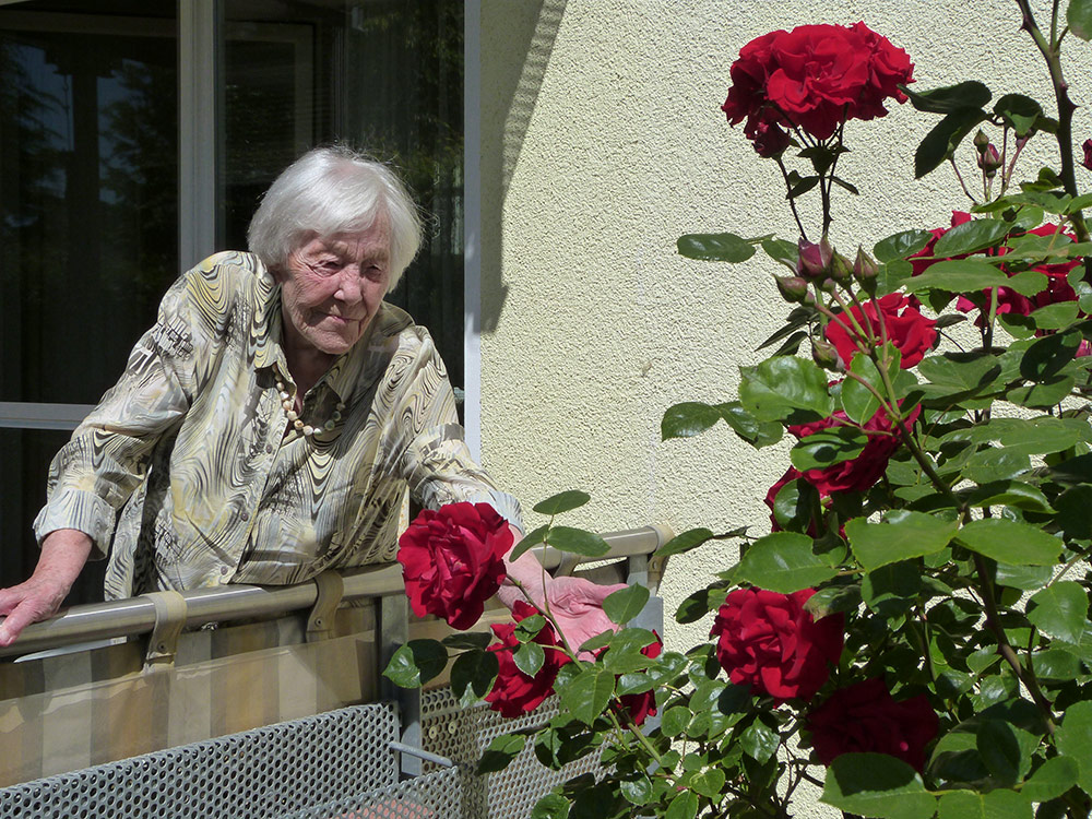 Eine Frau schaut sich die Rosen vor Ihrem Balkon an