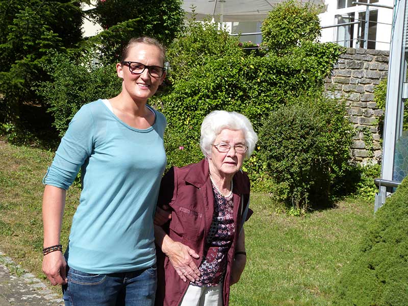 Mitarbeiterin mit Bewohnerin im Garten